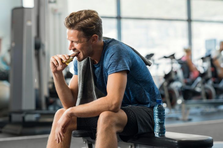 Athletic man eating a protein bar