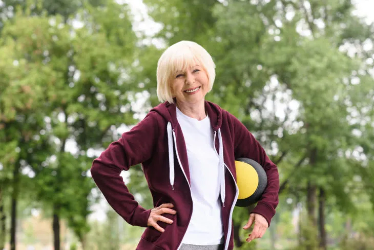 woman smiling with medicine ball under arm
